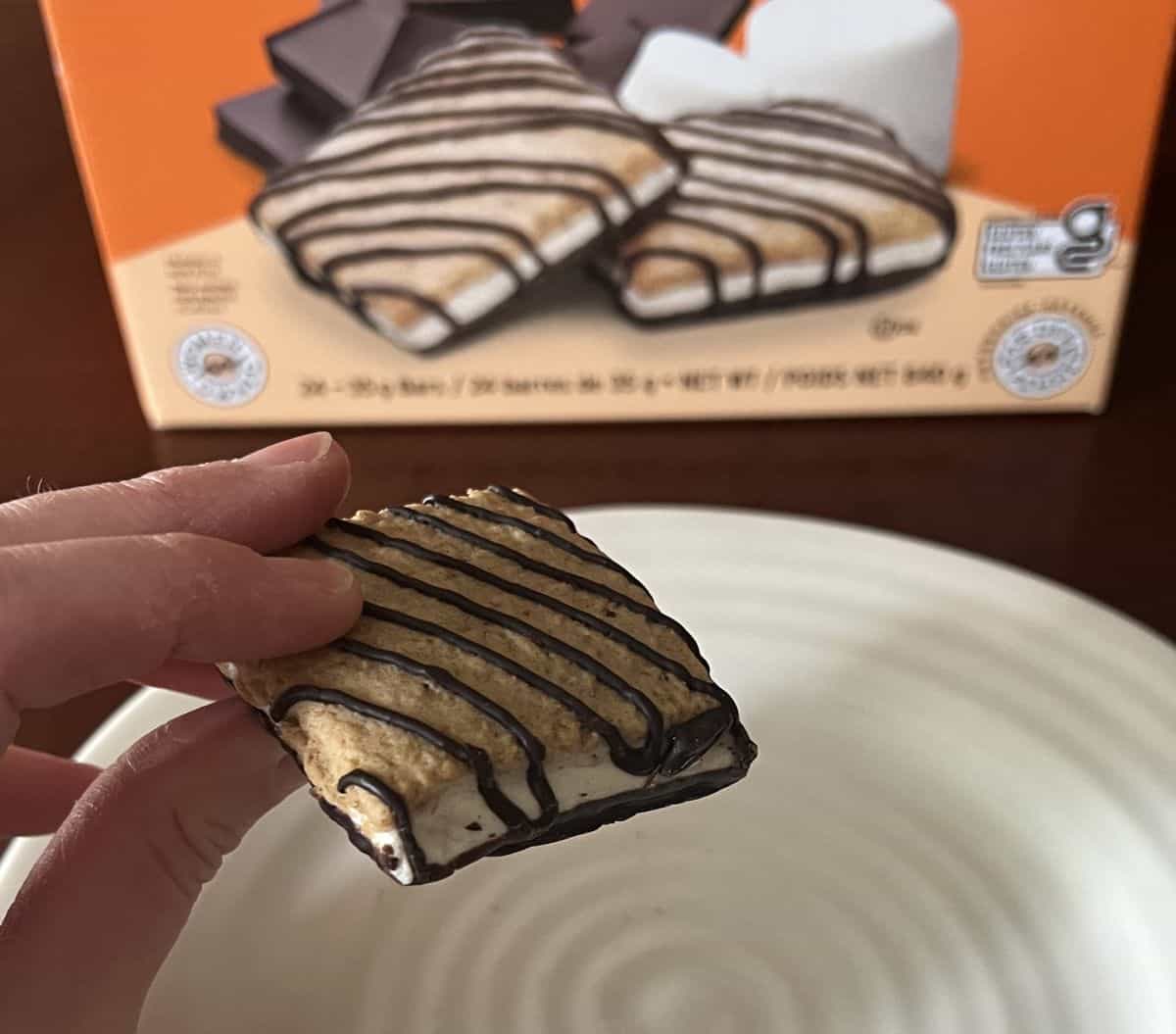 Image of a hand holding one Costco Five Peaks S'mores Bar hovering over a white plate.