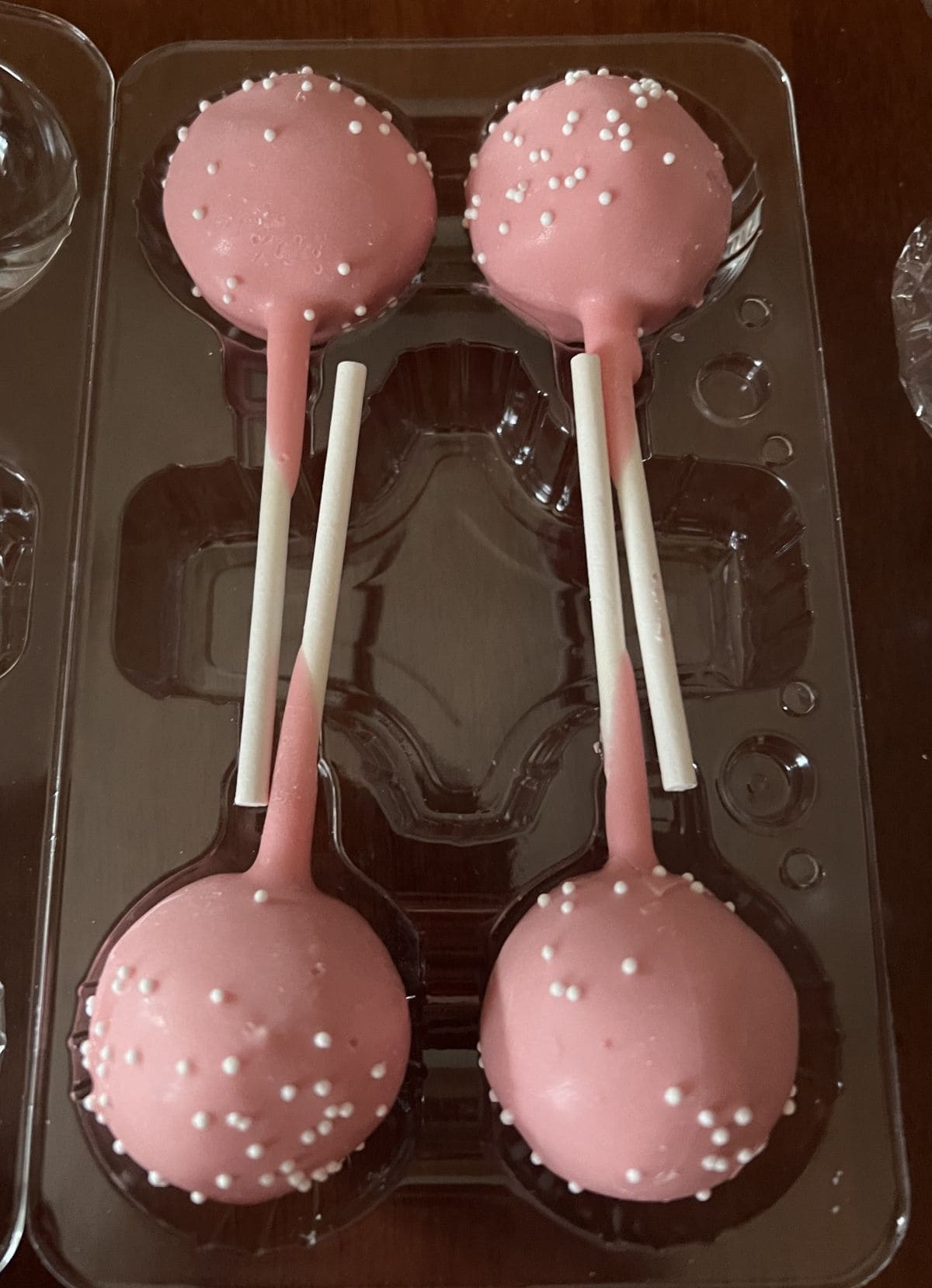 Image of four pink cake pops in a plastic container.