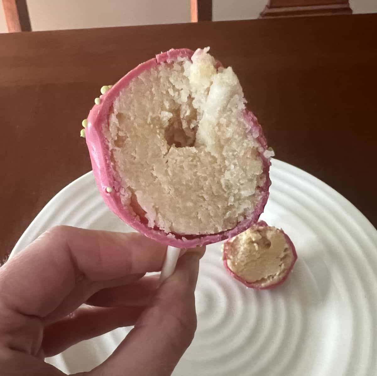 Image of a cake pop with a bite taken out of it so you can see the center.