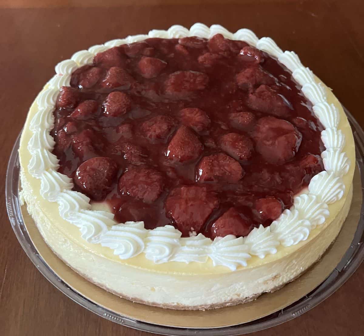 Image of the cheesecake sitting on a table with the lid off and it has not been sliced yet.