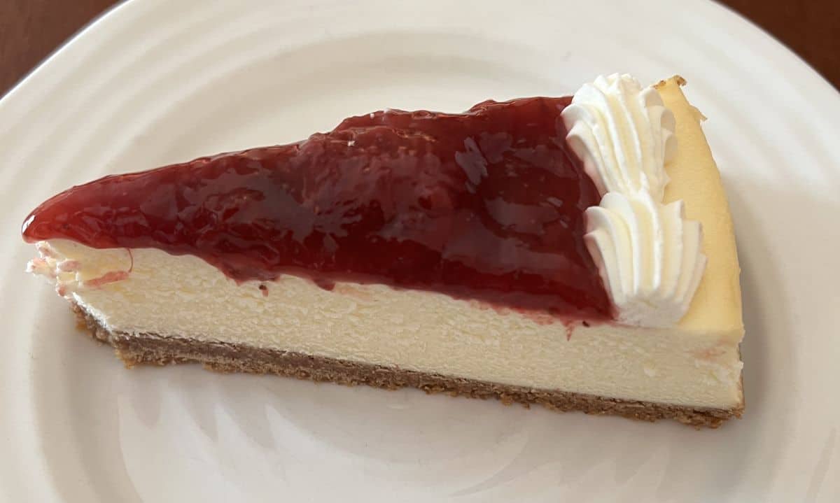 Image of one slice of cheesecake served on a white plate.