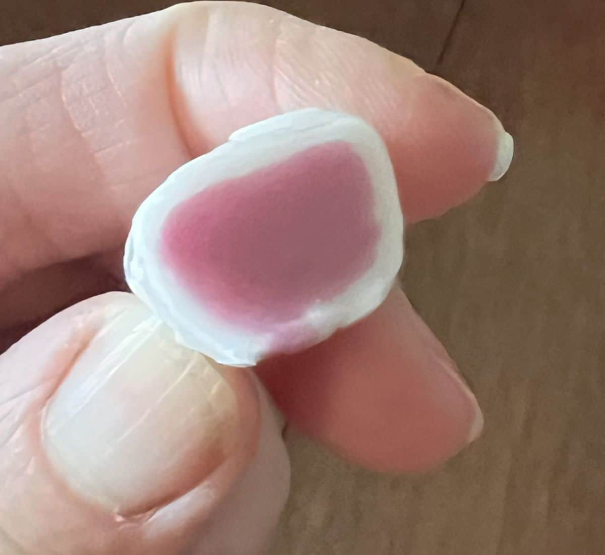 Image of a hand holding one grape flavored Hi Chew close to the camera.