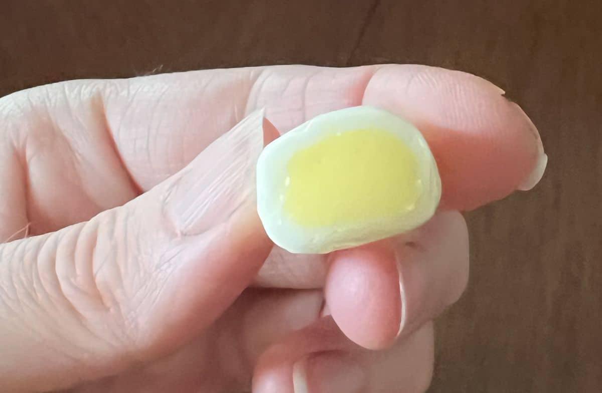 Image of a hand holding one mango Hi Chew close to the camera.