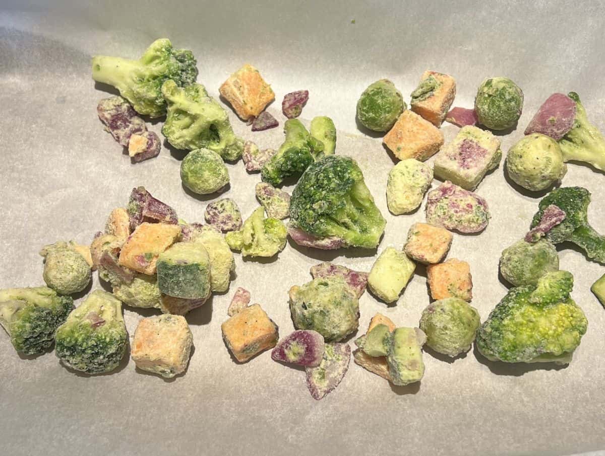 Image of the frozen vegetables on a parchment lined baking tray.