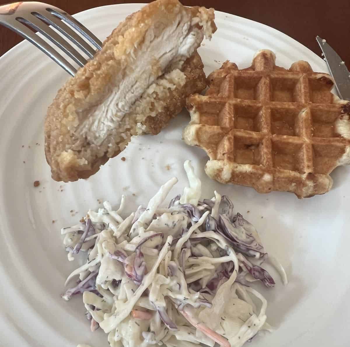 Closeup image of a fork with a piece of breaded chicken on it cut so you can see the inside of the chicken.