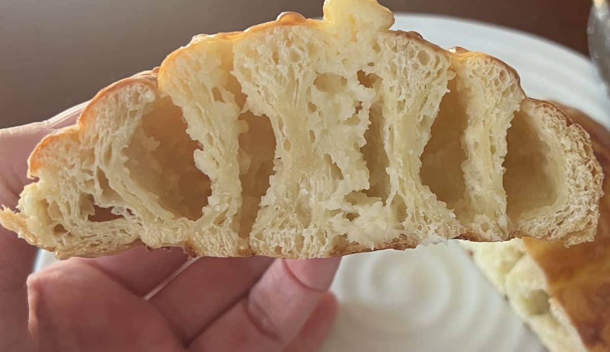 Closeup image of  hand holding one Kirkland Signature Cheese Swirl cut in half so you can see the middle.