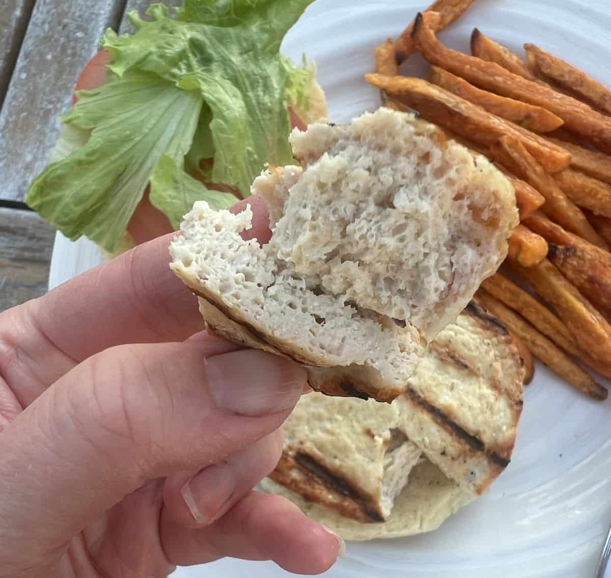 Image of a hand holding one piece of the chicken breast burger so you can see the inside. 