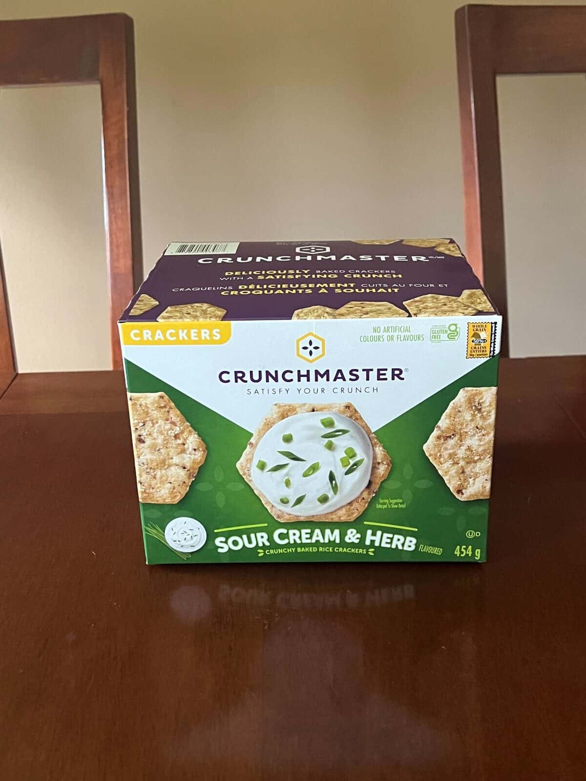 Image of the Costco Crunchmaster Sour Cream & Herb Crackers sitting on a table unopened. 