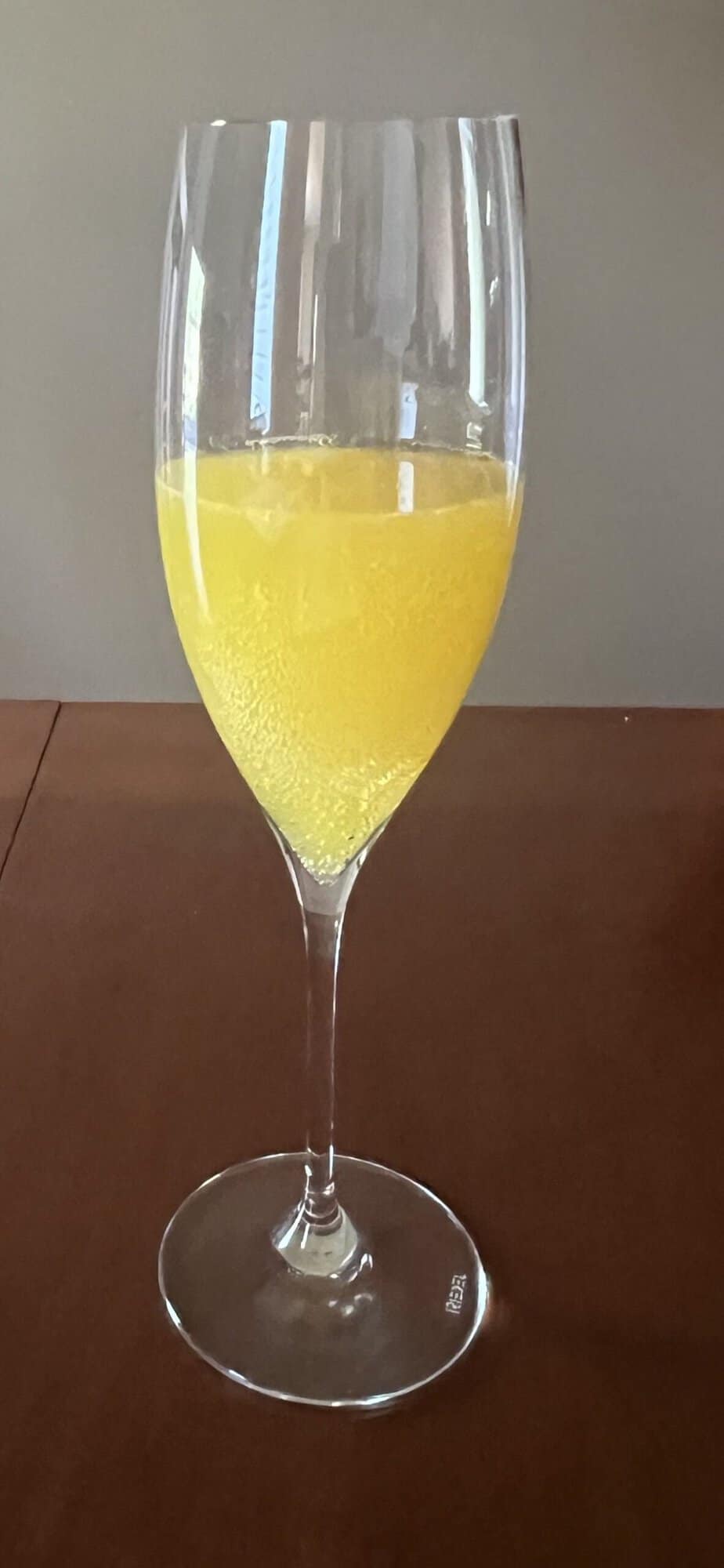 Image of one glass of mimosa in a champagne flute sitting on a table.