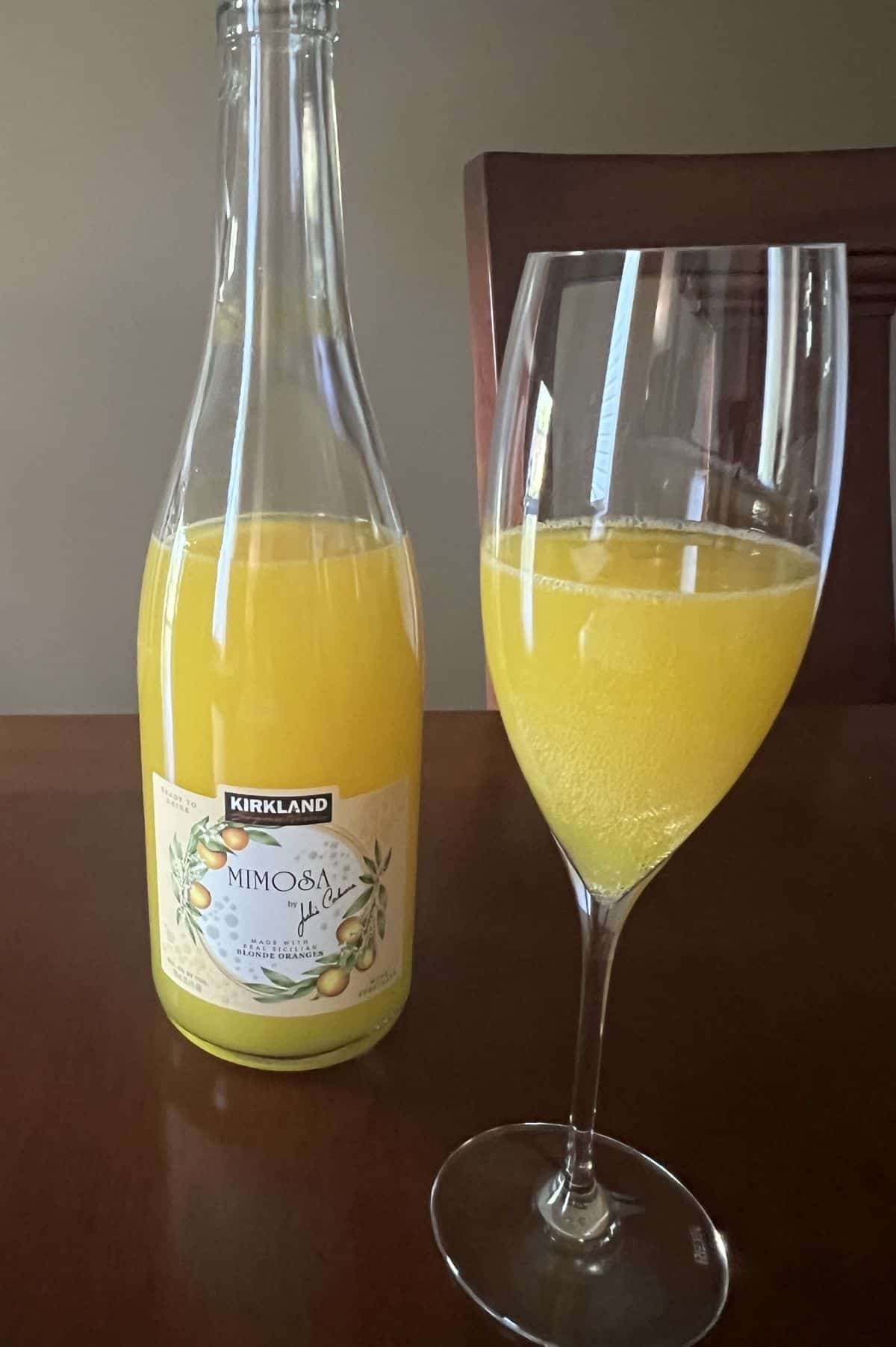 Image of a glass of mimosa beside the bottle of mimosa.