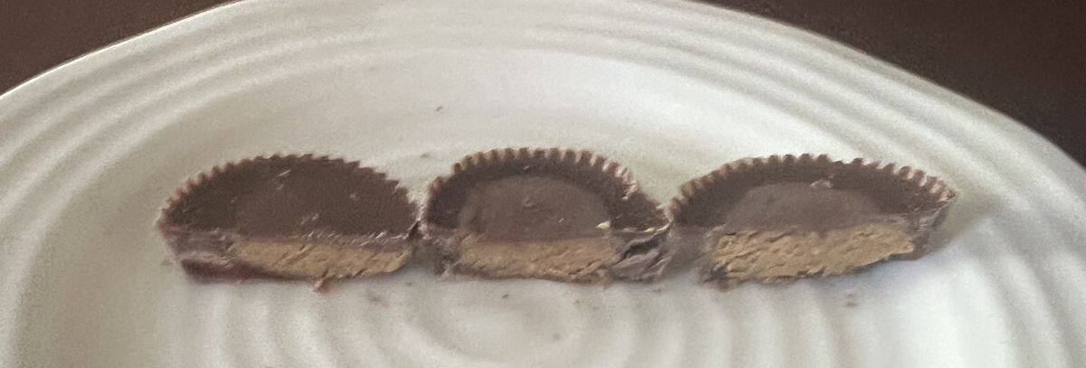 Image of three Reese's peanut butter cups cut in half served on a white plate.