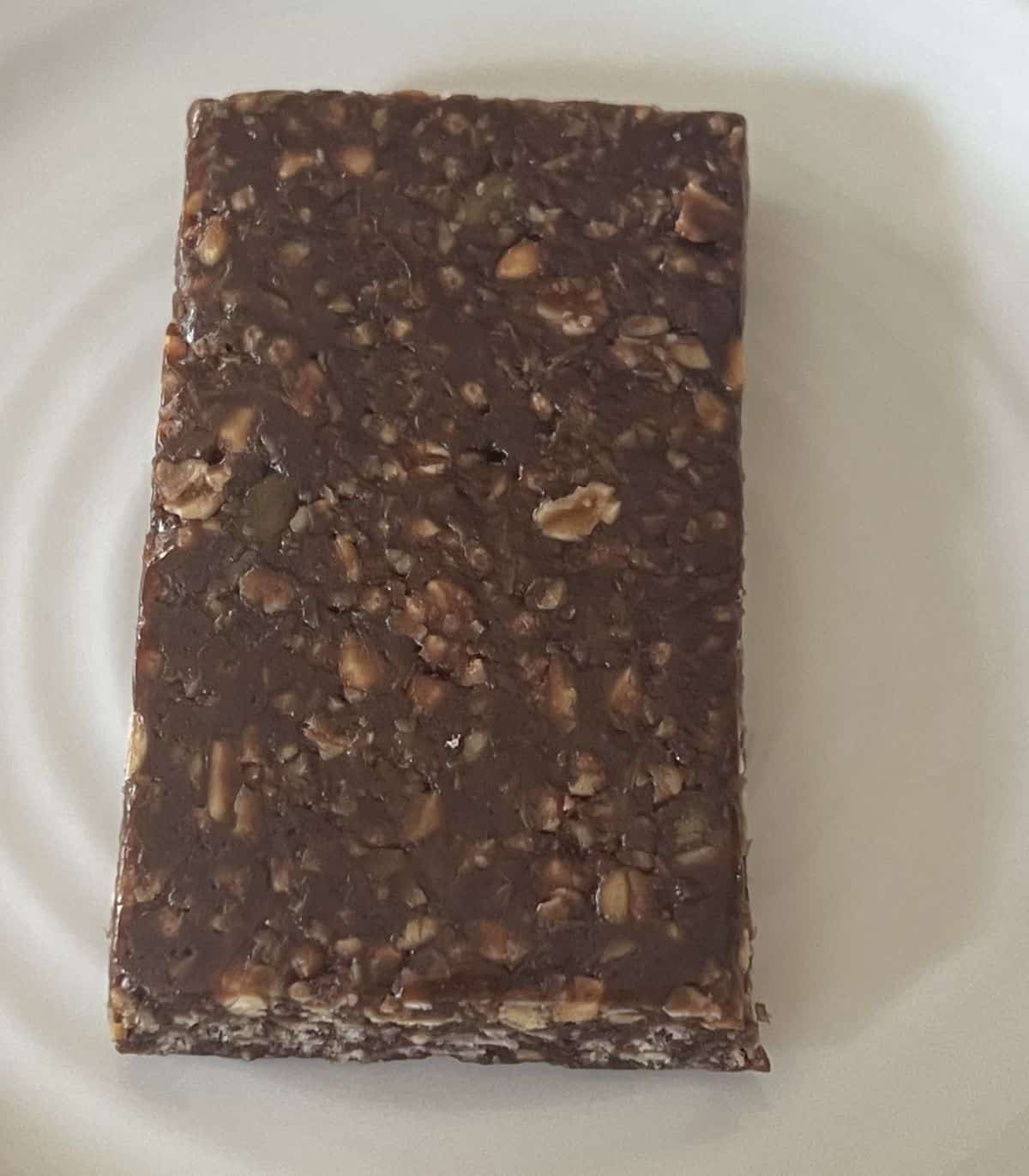 Top down image of one dark chocolate peanut butter bar served on a white plate.