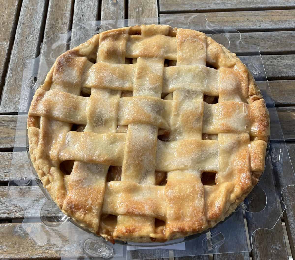 Top down image of one whole Costco Kirkland Signature Homestyle Apple Pie sitting on a table with the lid off. 