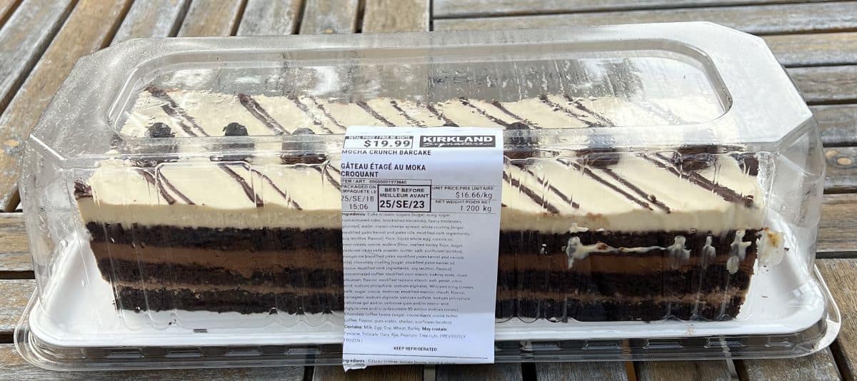 Image of the Costco Kirkland Signature Mocha Crunch Cake unopened and sitting on a table outside.