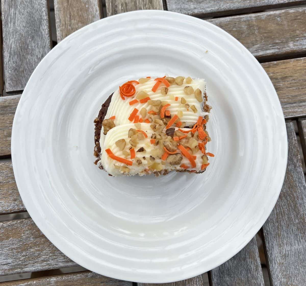 Top down image of one piece of carrot cake served on a white plate.