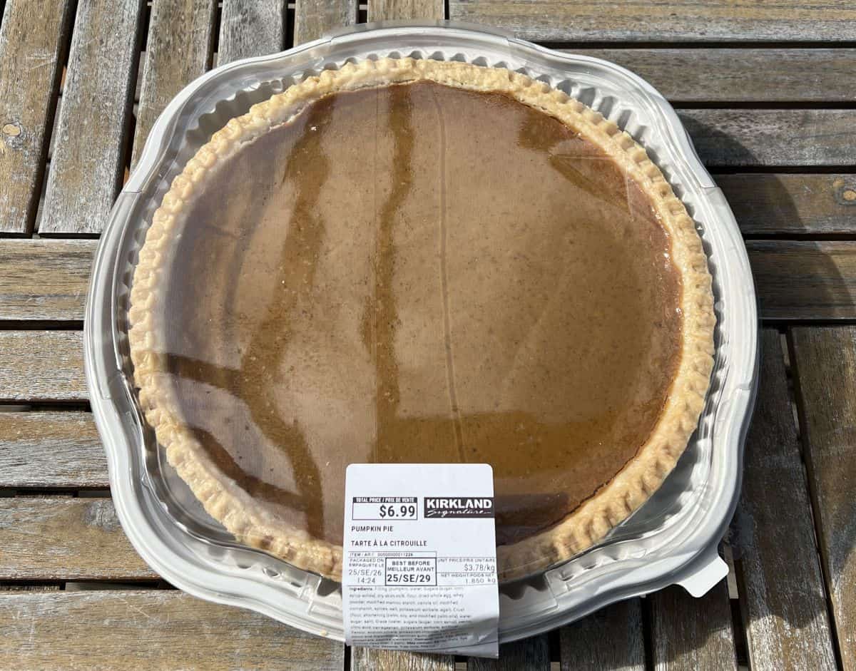 Top down image of the Costco Kirkland Signature Pumpkin Pie unopened sitting on a table outside. 