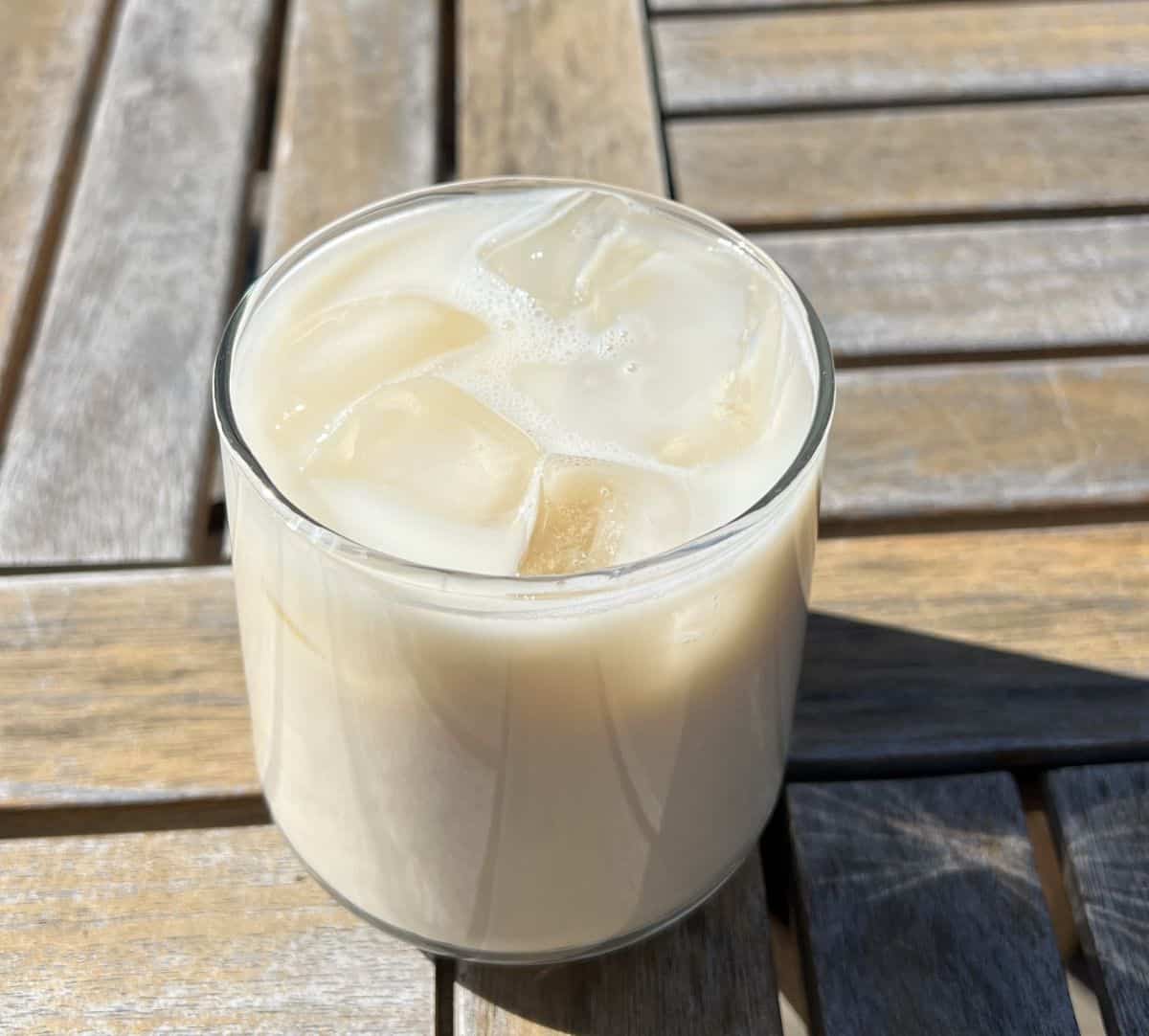 Top down image of one Premier Protein Pumpkin Spice protein shake poured and served into a clear glass with ice.