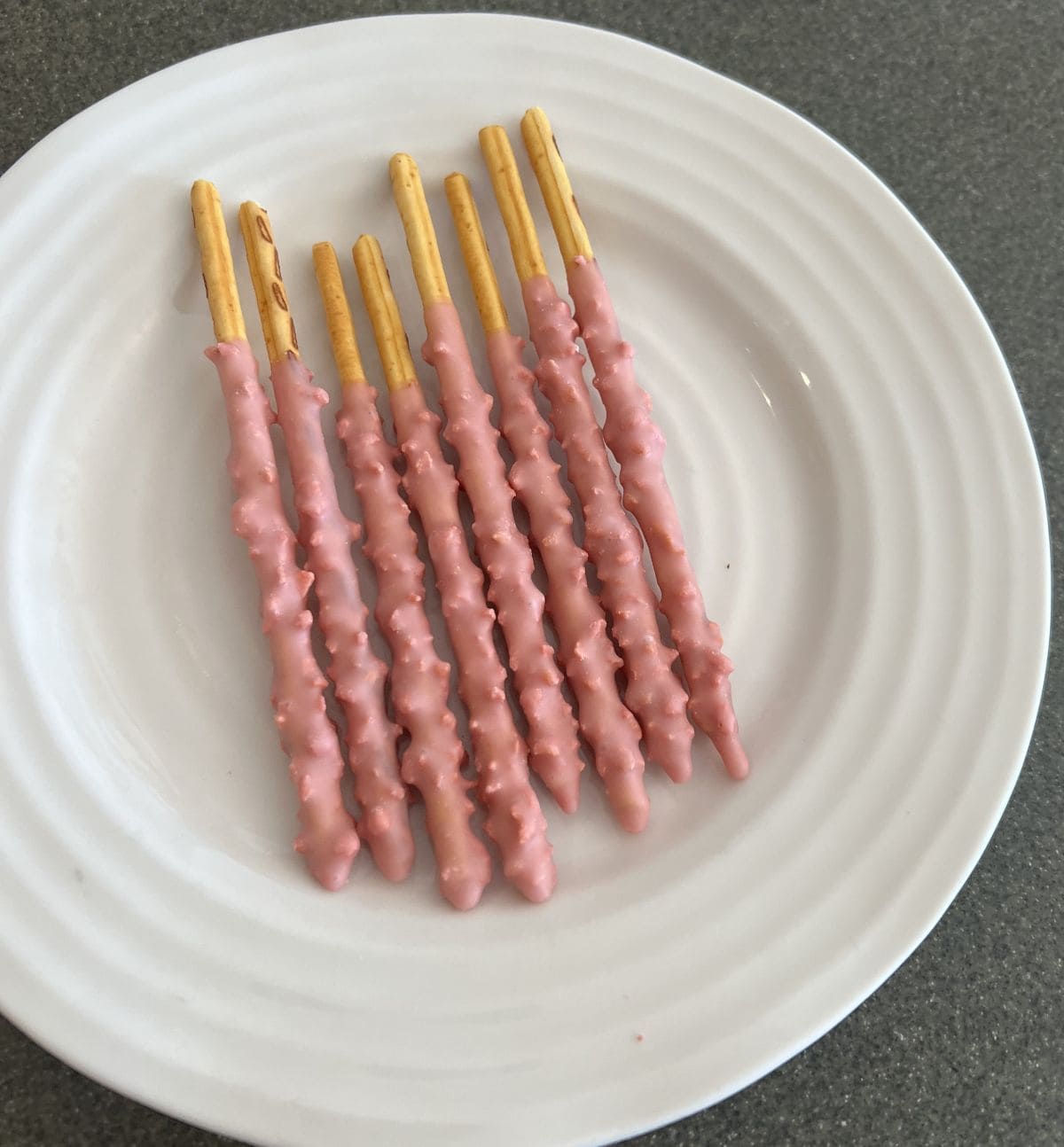 Top down image of a plate of eight Pepero sticks served on a white plate. 