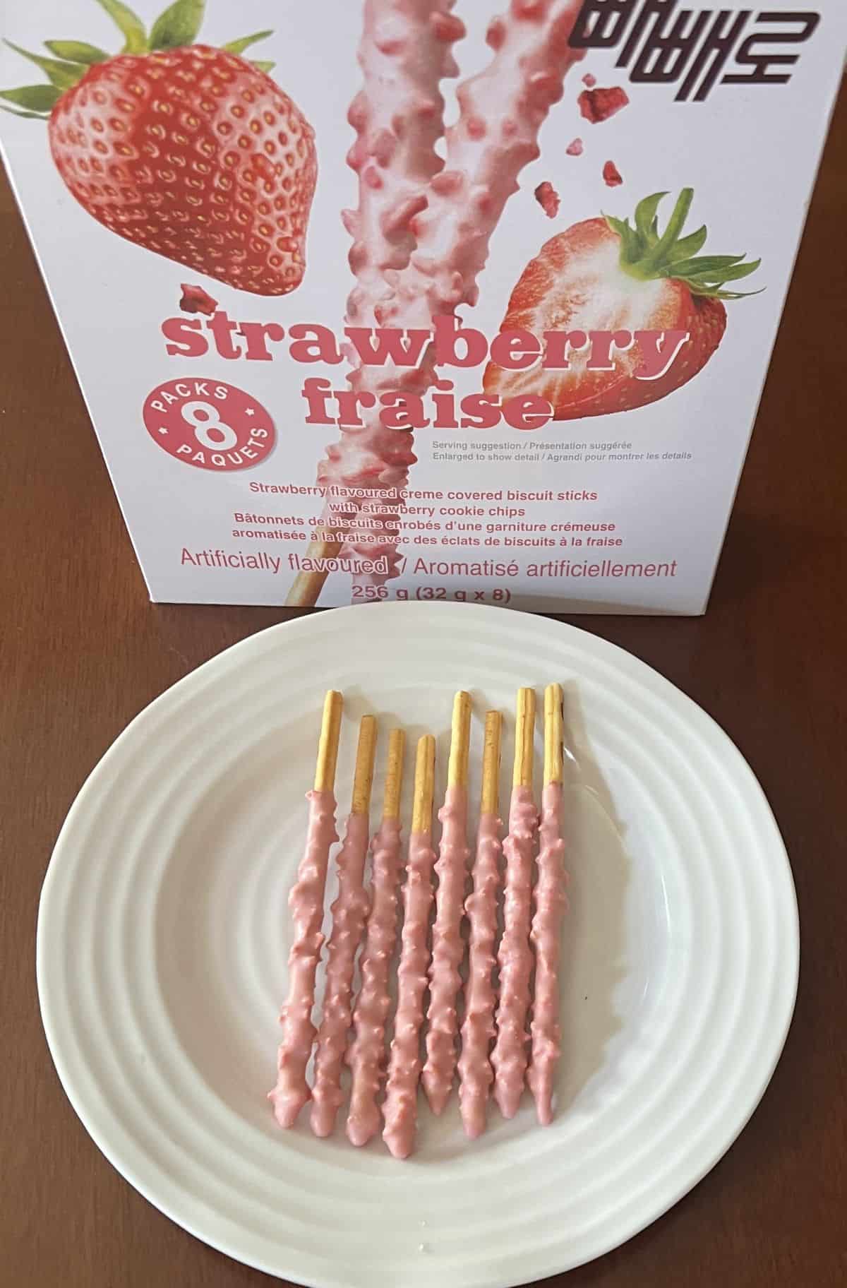 Image of the Pepero biscuit sticks served on a white plate in front of the box.