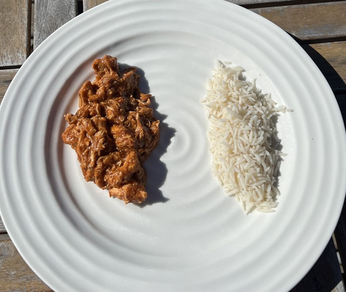 Top down image of chicken tinga served on a white plate beside white rice.