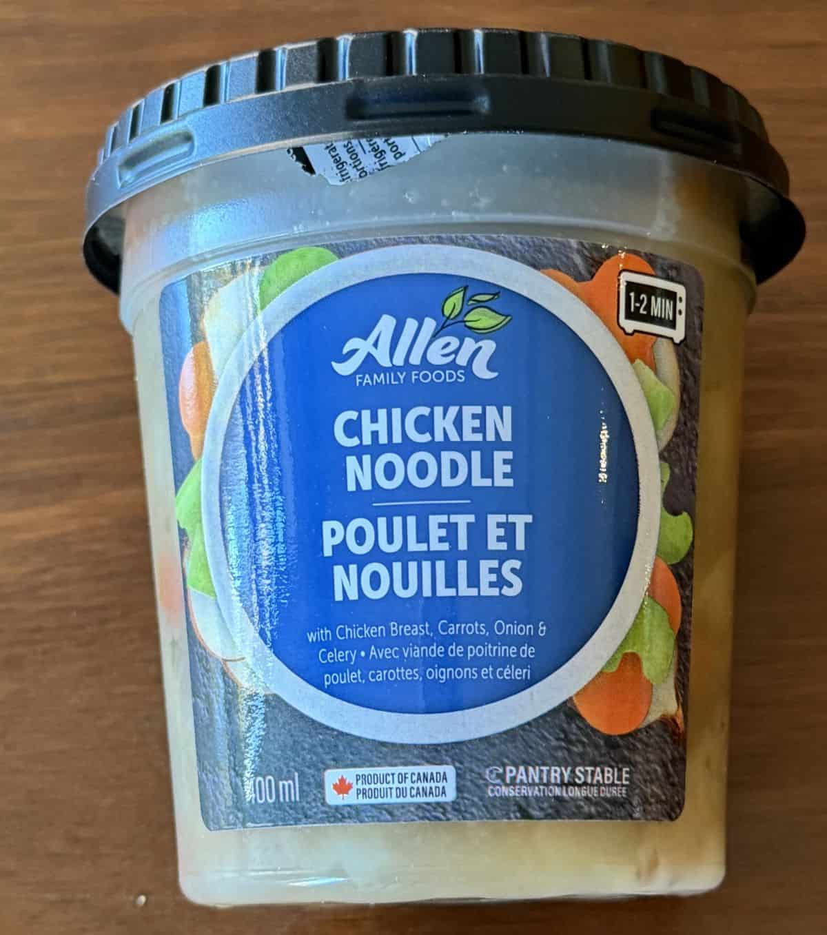 Image of the individual container of the chicken noodle soup, sitting on a table.
