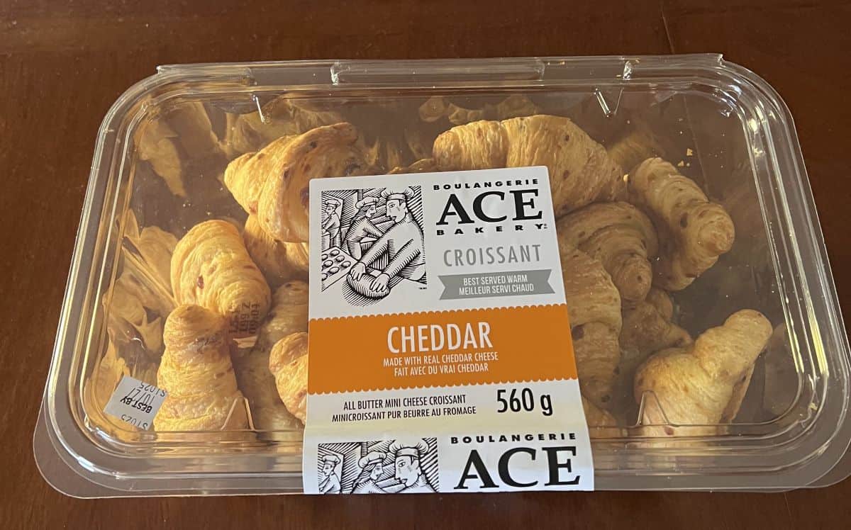 Image of the Costco Ace Bakery Mini Cheese Croissant container sitting on a table unopened.