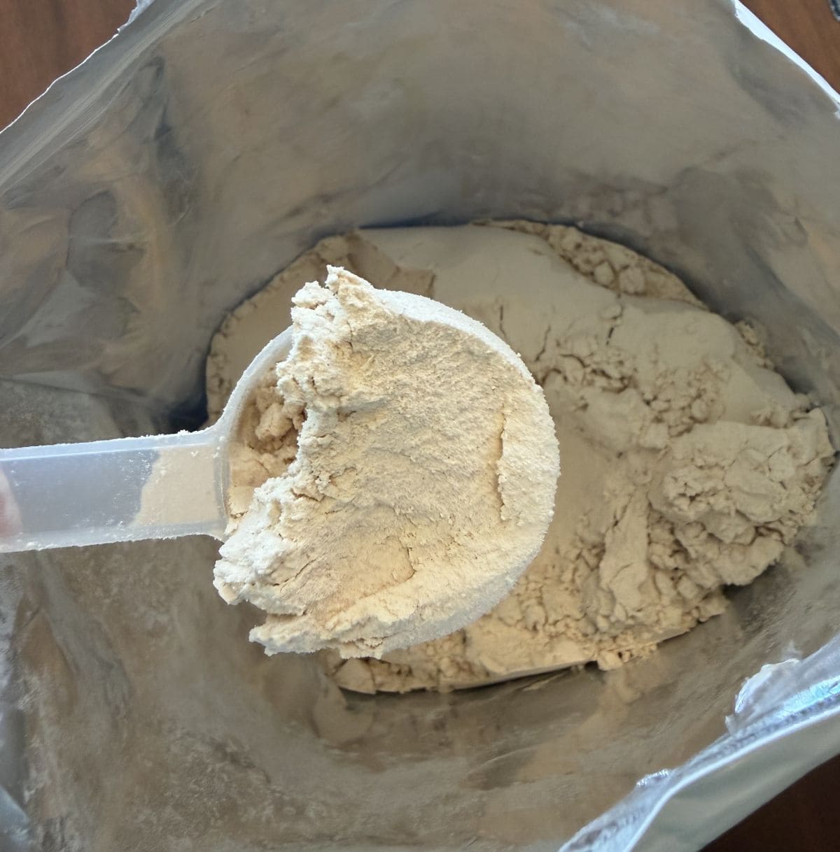 Top down image of the open bag of protein powder so you can see the powder and scoop in the bag.