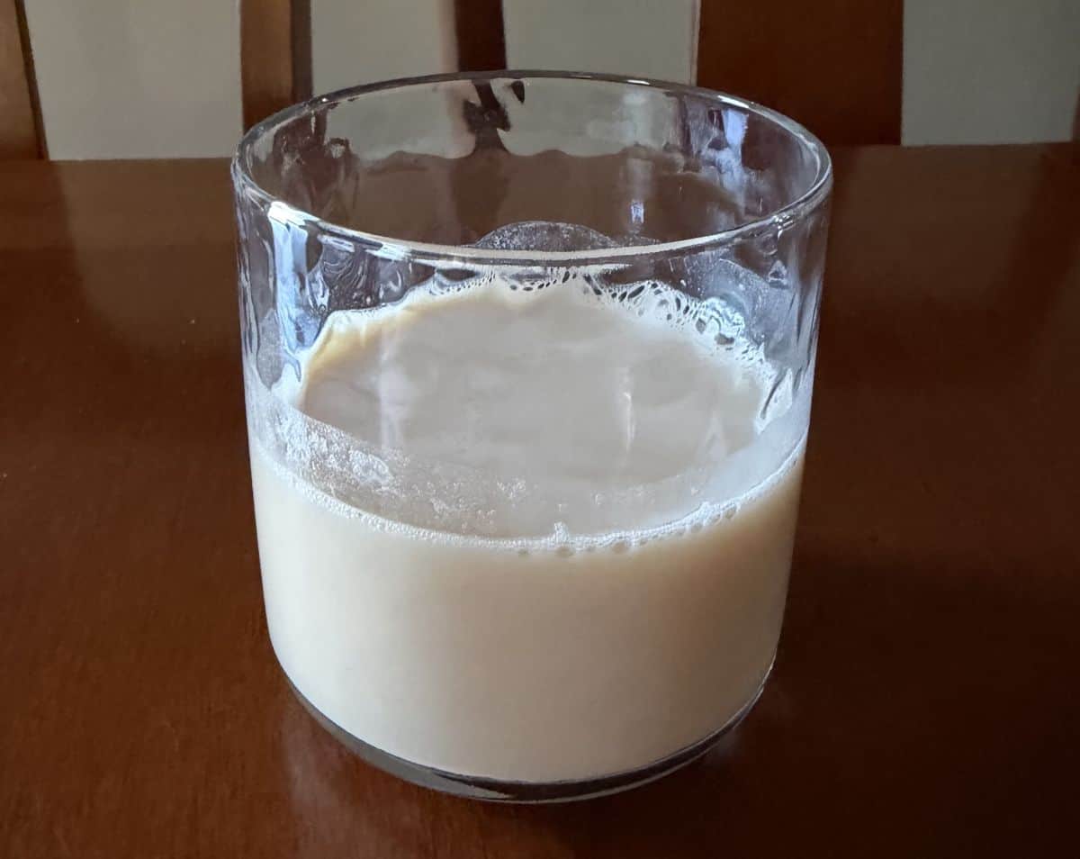 Image of a clear glass sitting on a table with the protein shake in it.