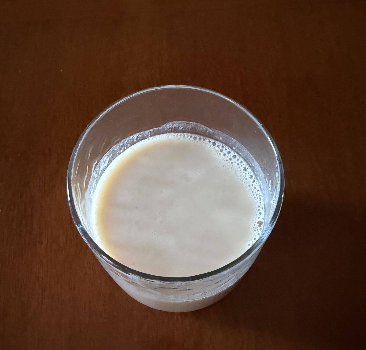 Top down image of the protein shake in a clear glass sitting on a table.