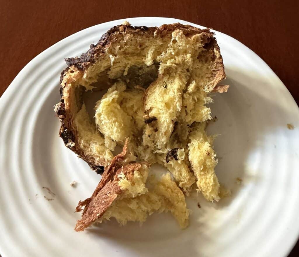 Top-down image of a slice of panettone served on a white plate. 