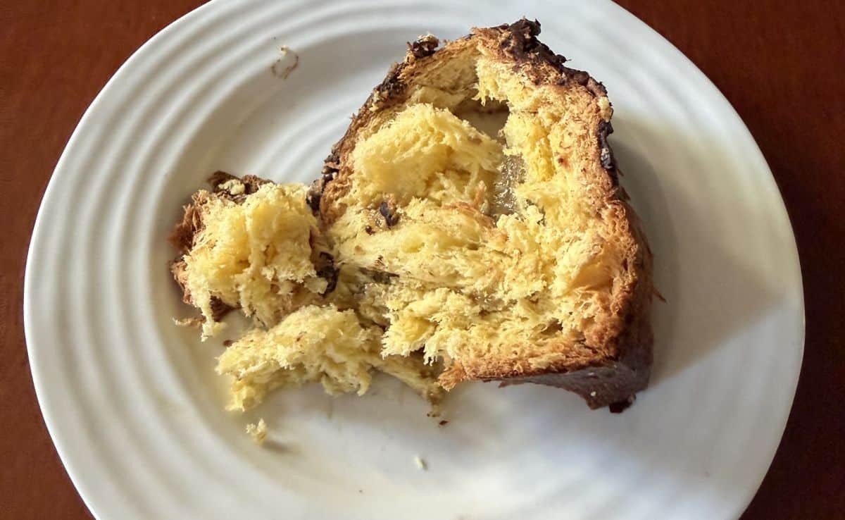 Image of one slice of panettone served on a white plate so you can see the pistachio cream. 