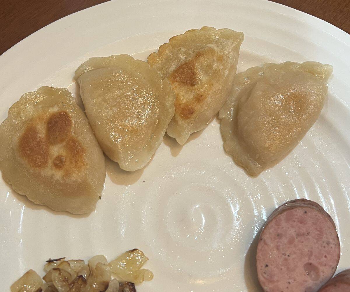 Image of four cooked perogies on a white plate. 