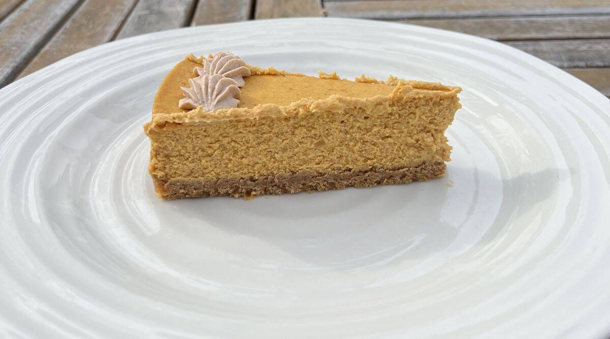 Sideview image of one slice of cheesecake served on a white plate.