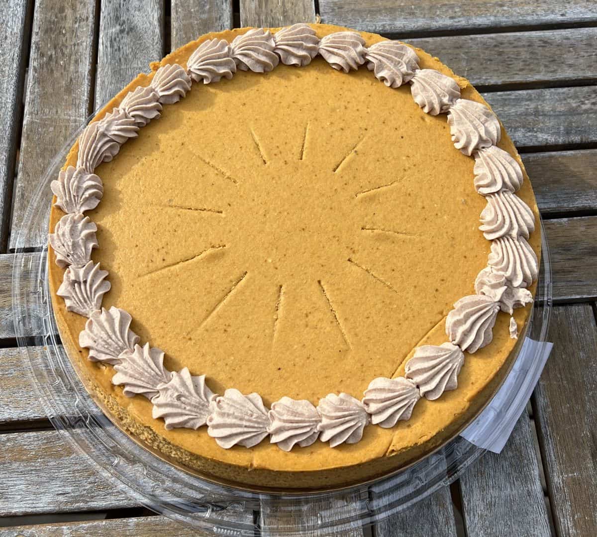 Top down image of the entire Costco Kirkland Signature Pumpkin Cheesecake sitting on a table outside with the lid off.