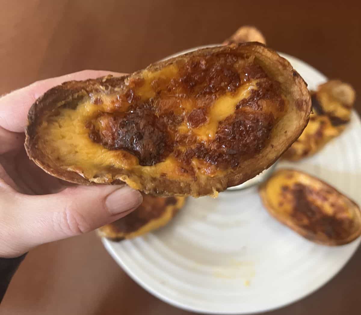 Closeup image of one potato skin, you can see melted cheese and bacon.
