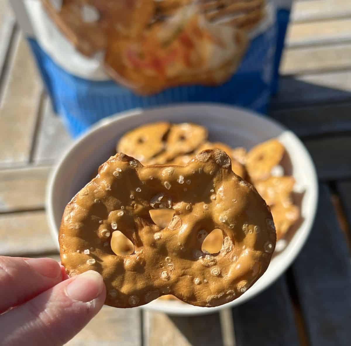 Closeup image of a hand holding one pretzel crisp close to the camera. 