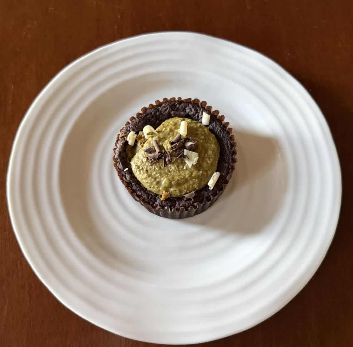Top down image of one brownie served on a white plate.