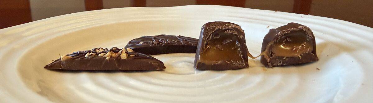 Image of four chocolates served on a white plate and cut in half so you can see the center. 