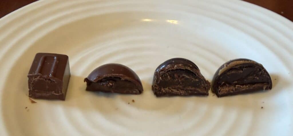Image of four chocolates served on a white plate and cut in half so you can see the center.