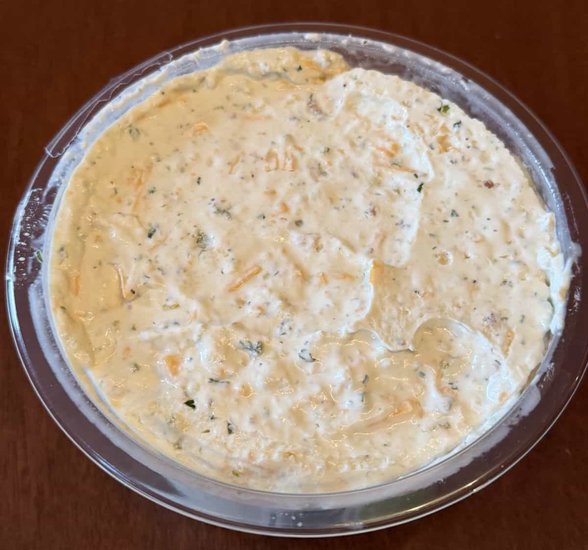 Top down image of an open container of the Costco Good Foods Creamy Cheddar Jalapeno with Bacon Dip sitting on a table.