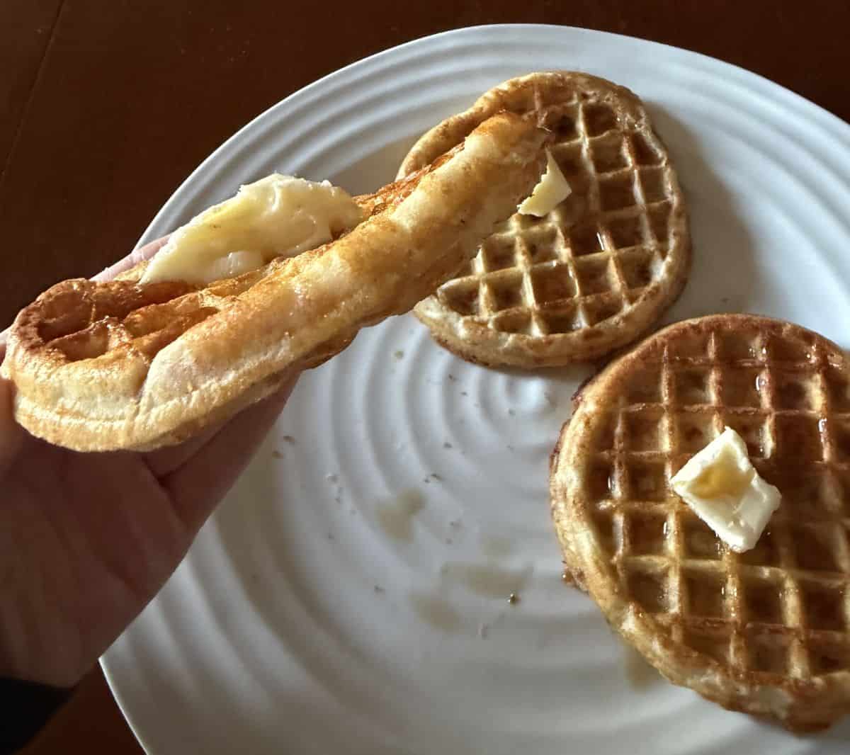 Image of a hand holding one waffle close to the camera so you can see how thick the waffle is.