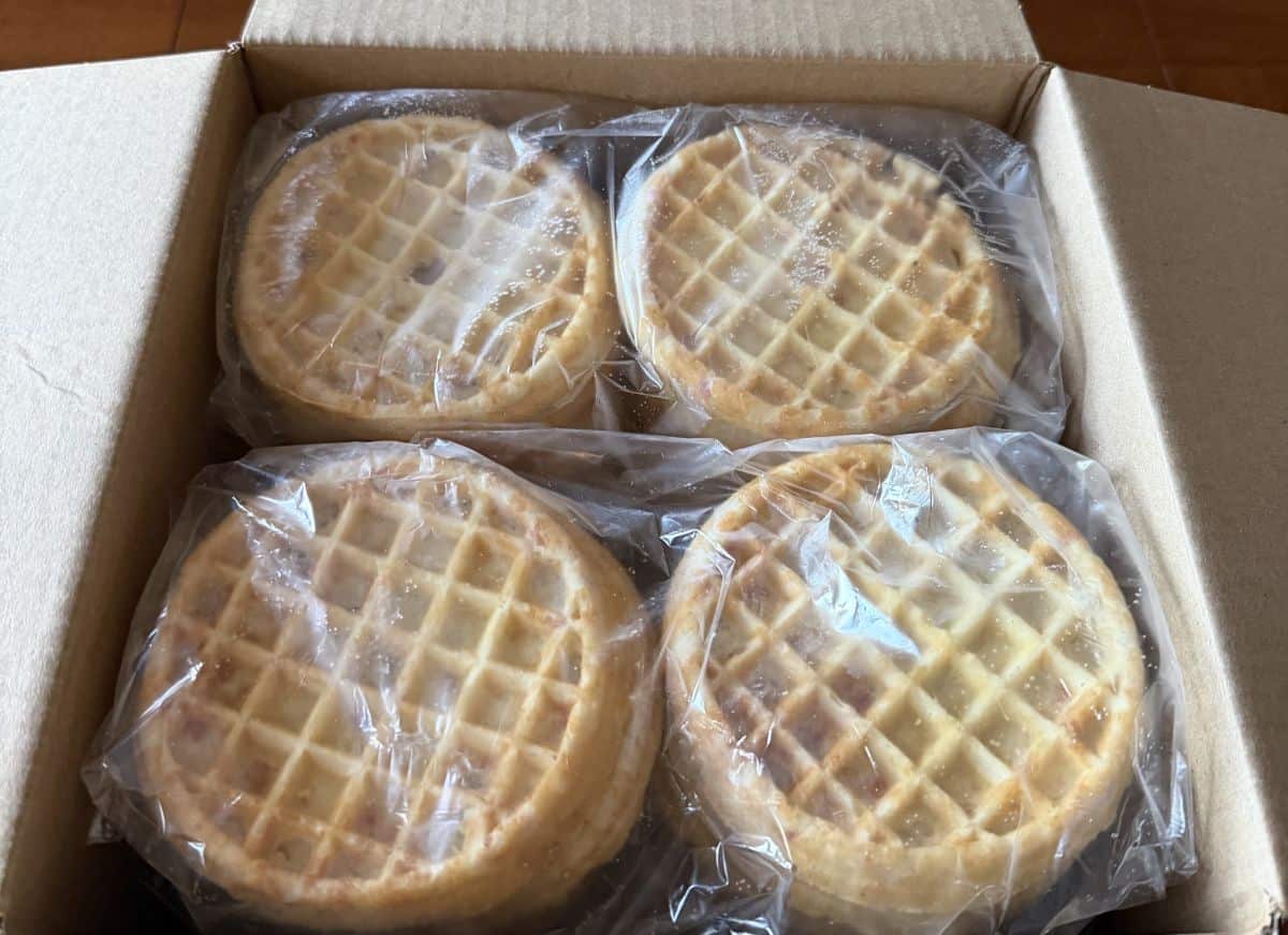 Image of four plastic sleeves of waffles sitting in a cardboard box.