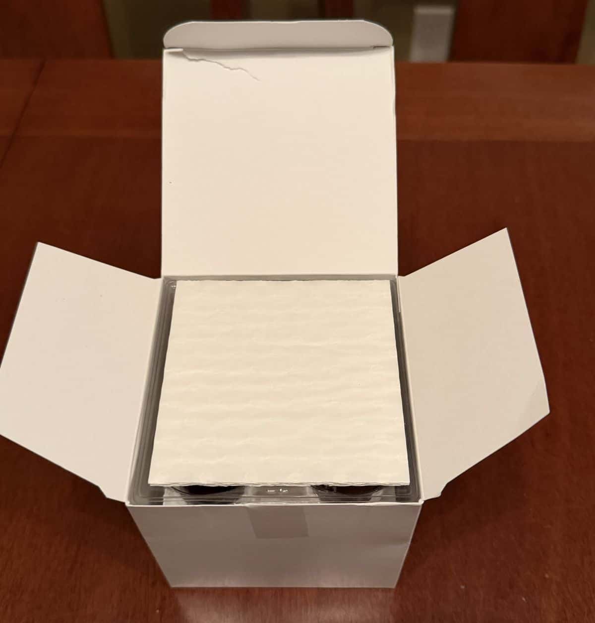 Image of an open box of chocolates showing the top has a piece of paper protecting the chocolates. 