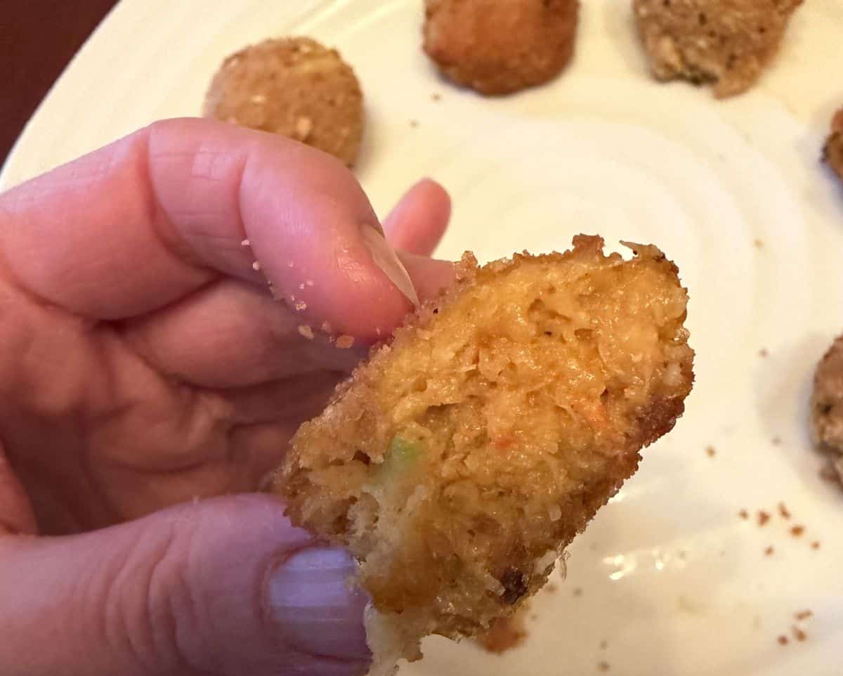 Image of a hand holding one crab bite close to the camera.
