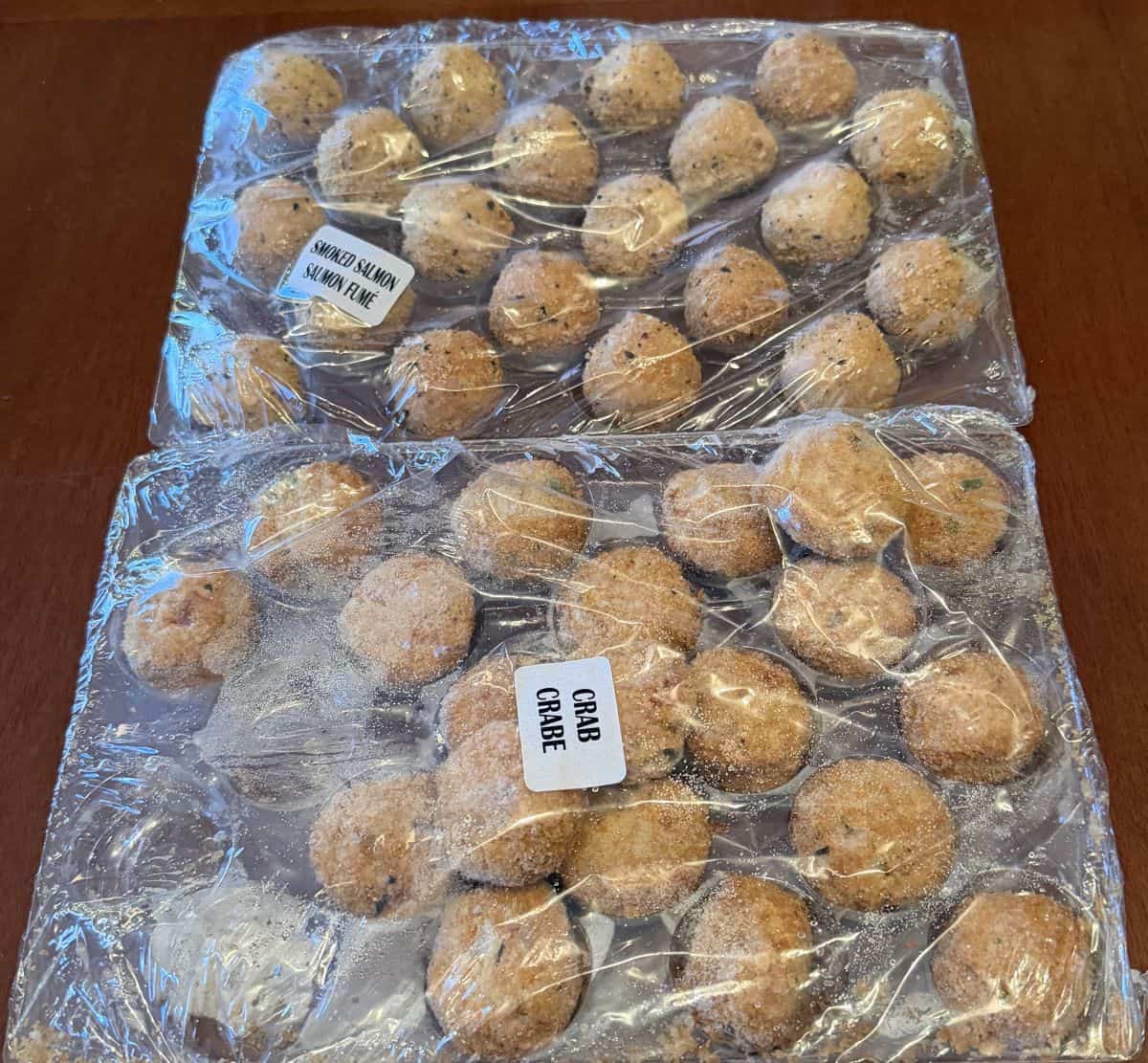 Image of two wrapped plastic trays with salmon and crab bites in the trays.