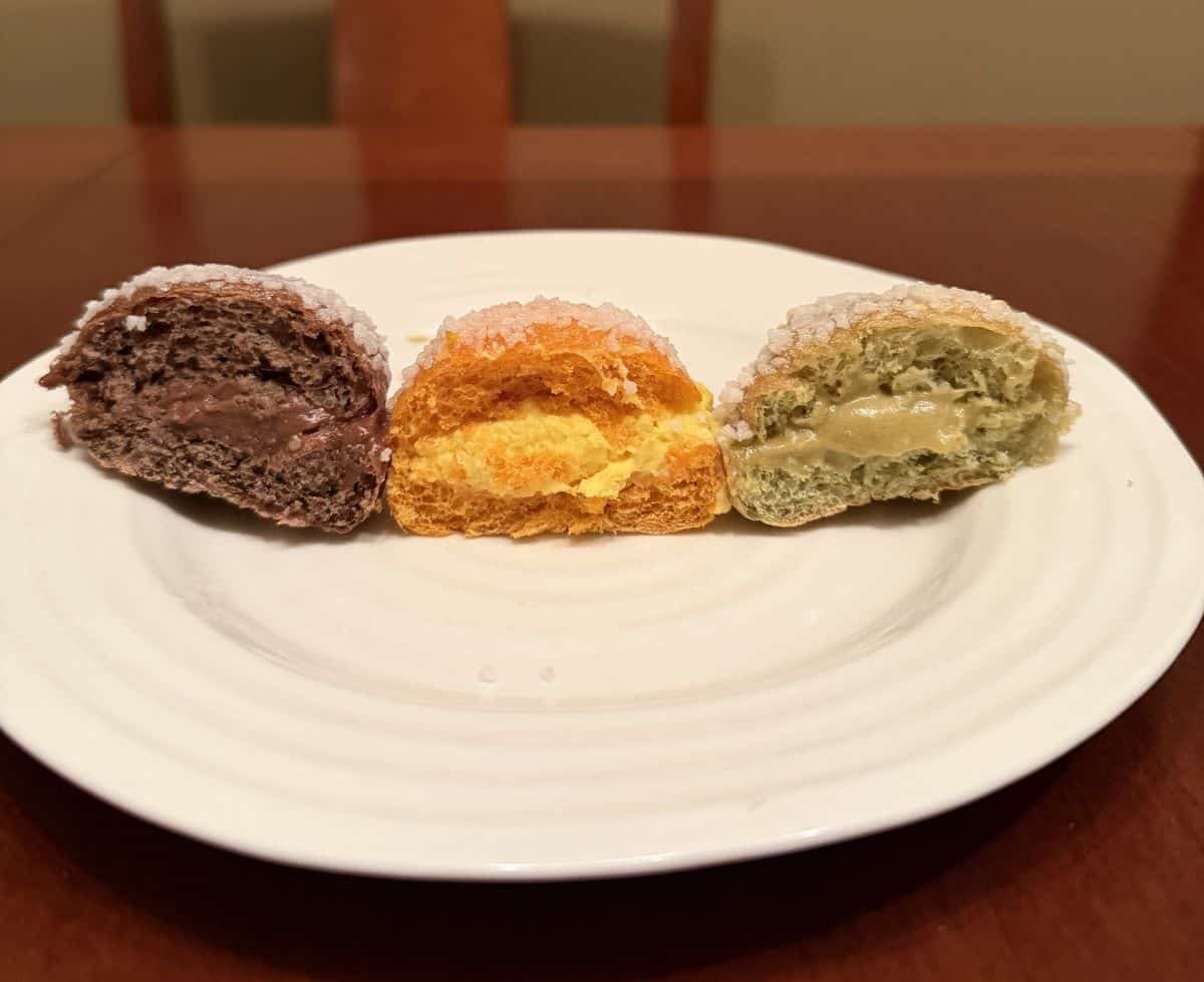 Image of three mini brioche cut in half so you can see the pastry cream, served on a white plate.