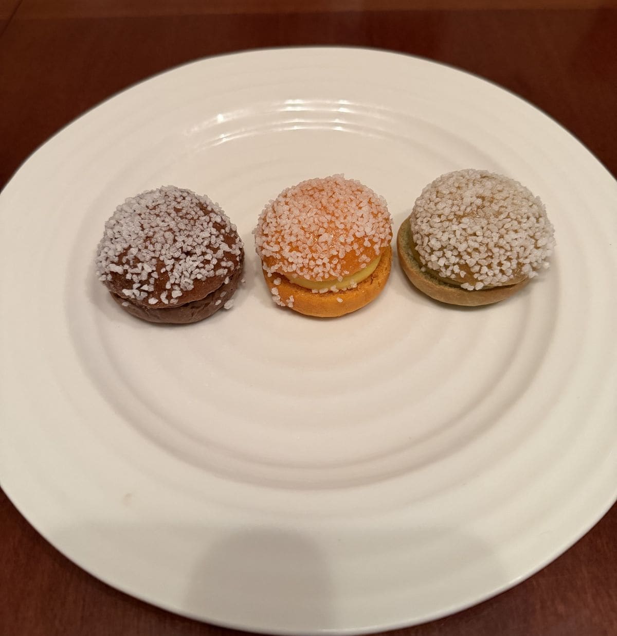 Three mini brioche in three different flavors served on a white plate.