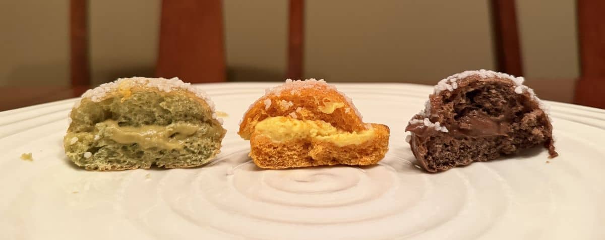 Image of three mini brioche served on a white plate cut in half so the filling is noticeable.