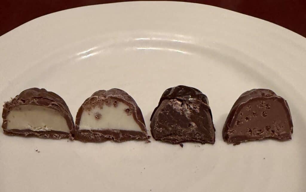 Image of four truffles that have each been cut in half served on a white plate so you can see the center of the truffles.