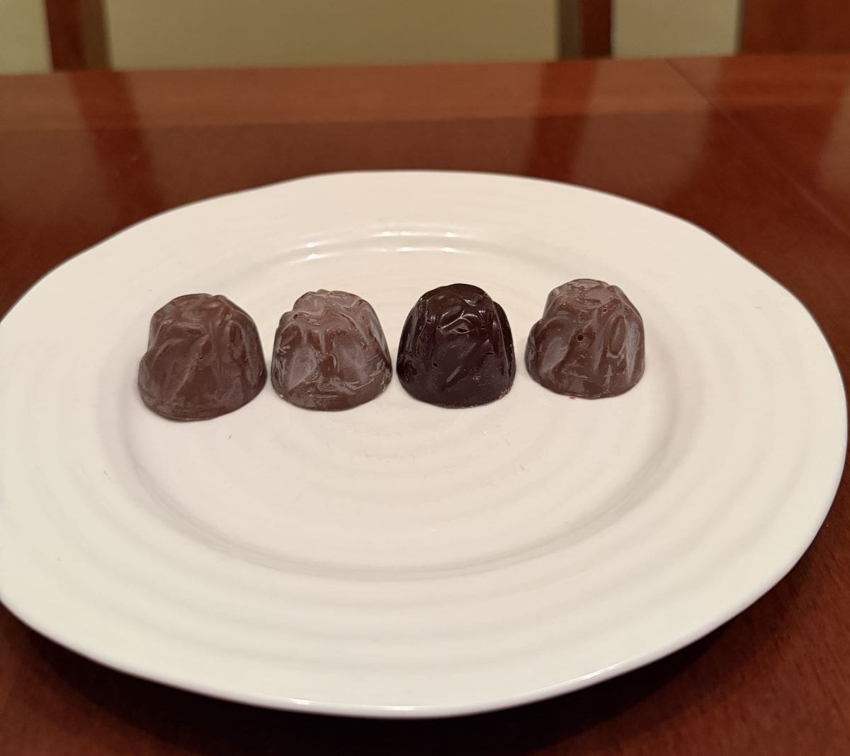 Image of four unwrapped truffles served on a white plate.